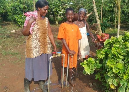 Mrs Sekindi with her daughters at their tap stand at their home in Wajinja village edit